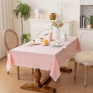 Detail of pink cotton tablecloth featuring decorative white pom-pom fringe edges