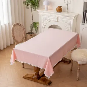 Detail of pink rectangular tablecloth with decorative white pom-pom fringe edging