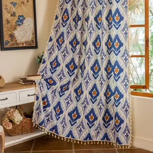 Close-up of geometric pattern curtain with cream tassel fringe and woven texture