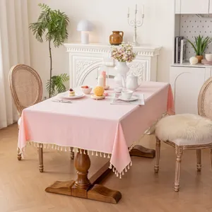 Light pink cotton linen tablecloth with tassel edges in a warm French vintage dining room