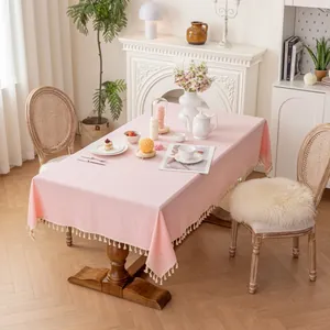 Pink rectangular cotton linen tablecloth featuring ivory fringe details on a wooden table