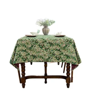 Floral rectangle tablecloth in green with tiny white and pink flowers on vintage wood