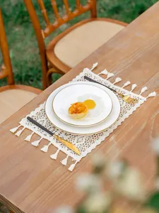 Détail d'un set de table en crochet bohème avec motifs floraux ajourés et franges