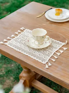 Gros plan d'un set de table en dentelle au crochet avec pompons de style bohème sur bois