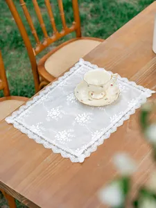 Gros plan d'un élégant set de table en dentelle avec broderie florale sur une table en bois