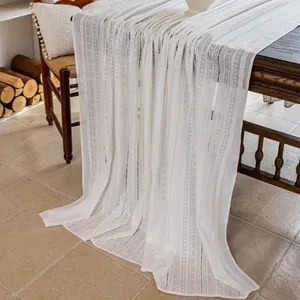 Macro shot of white cotton table runner featuring geometric embroidery and hollow lace details