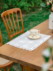 Gros plan sur la broderie de dentelle florale du set de table vintage aux bords festonnés