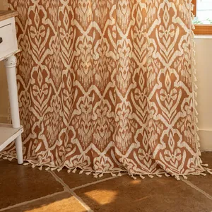 Close-up of Bohemian geometric printed curtain with textured beige tassels and warm orange tones