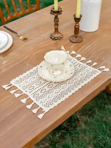 Détail de set de table en dentelle bohème avec glands faits main sur table en bois