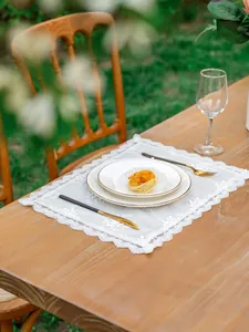 Détail de set de table en dentelle blanche avec broderie florale sur table en bois rustique