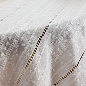 Macro shot of white cotton tablecloth showing delicate floral embroidery and cutouts