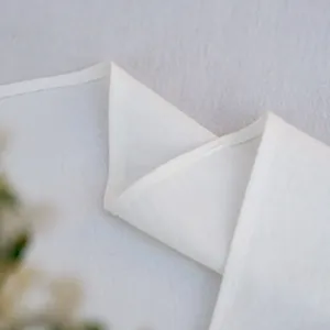Detailopname van het witte minimalistische tafelkleed met fijne zoomranden en textuur