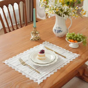 Détail de set de table en dentelle blanche avec broderie florale et bords festonnés