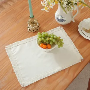 Détail de set de table rectangulaire crème à franges sur table en bois avec fleurs