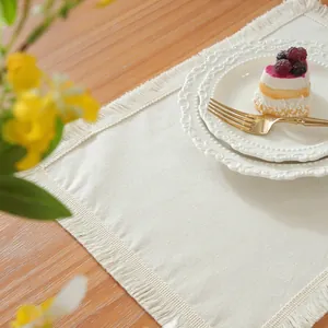 Gros plan d'un set de table rectangulaire crème à franges sur une table en bois naturel