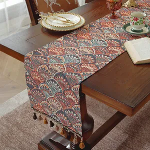 Dettaglio runner da tavola in jacquard verde con nappe decorative su tavolo in legno