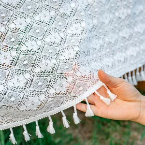 Detailed view of white boho lace tablecloth with floral patterns and soft white fringe