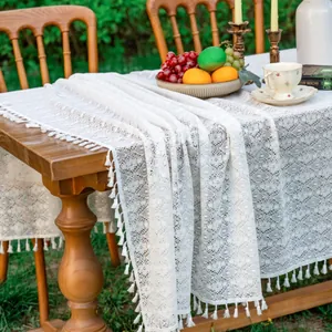 Detail of white hollow lace tablecloth featuring elegant fringe edges and boho pattern