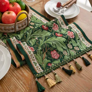 Detail van een bosgroene jacquard tafelloper met bloemmotieven en kleurrijke kwastjes