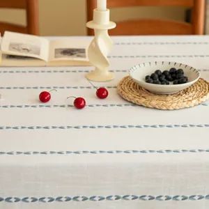 Detail van jacquardstof met blauwe bladpatronen en fijne franjes op wit modern tafelkleed