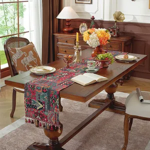 Dettaglio runner da tavola bohémien con motivi jacquard etnici e nappe decorative