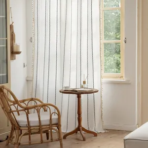 Detail of white striped curtain with black chain pattern and beige fringe tassels decoration