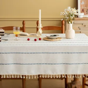 Detail van blauwe geometrische borduursels en franjes op een beige rechthoekig tafelkleed