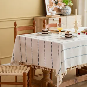 Detail van crèmekleurig tafelkleed met blauwe strepen en handgemaakte franjes