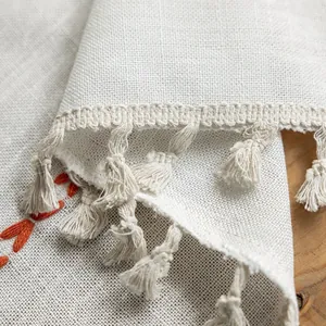 Close-up of white striped polyester curtain fabric with tassels and orange embroidery