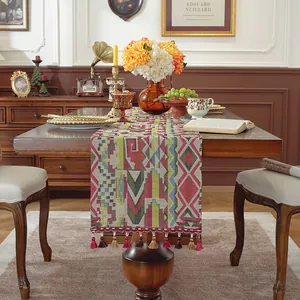 Dettaglio del runner da tavola jacquard con motivi geometrici e nappe su legno