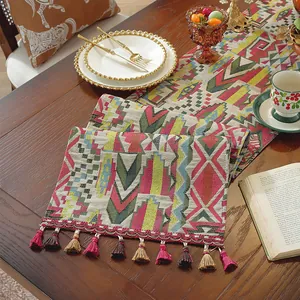 Dettaglio del runner da tavolo in tessuto spesso con motivi geometrici colorati e nappe