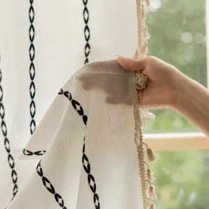 Detailed texture of beige striped curtain with black geometric patterns and fringe