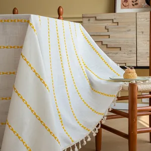 Detail van wit modern tafelkleed met gele geometrische borduurpatronen en franje rand