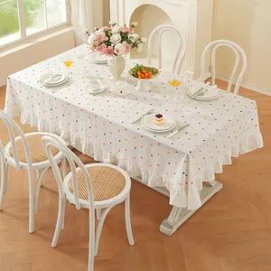 Détail de nappe rectangulaire blanche avec des pois colorés et une bordure à volants
