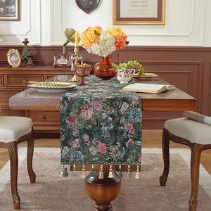 Dettaglio runner da tavolo boho verde scuro con motivi floreali e nappe pendenti