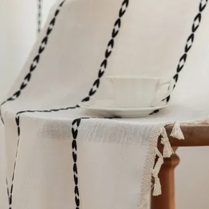 Detail of cream linen runner with black geometric embroidery and fringed edges on a chair