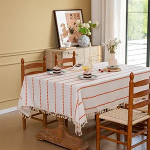 Detail van beige tafelkleed met rode geometrische borduursels en kwastjesrand