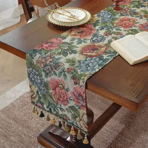 Dettaglio del runner da tavola vintage floreale con nappe su un tavolo di legno scuro