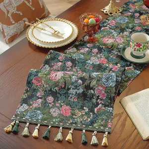 Dettaglio macro del runner da tavolo jacquard floreale verde scuro con nappe fatte a mano