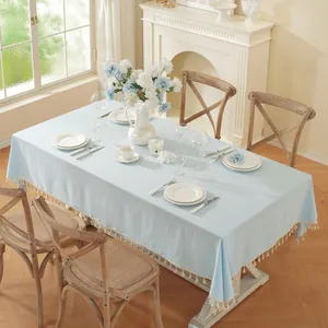 Detail of light blue linen tablecloth featuring white tassels and elegant textures