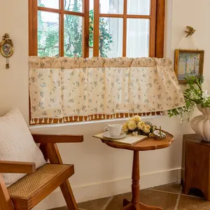 Close-up of floral cafe curtain with beige cotton linen fabric and tassel fringe detail