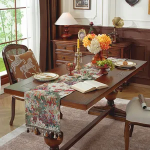 Dettaglio del runner da tavolo jacquard floreale vintage con nappine decorative su legno