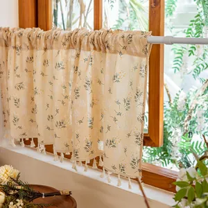 Detailed close-up of floral cafe curtain with cotton linen texture and white tassels