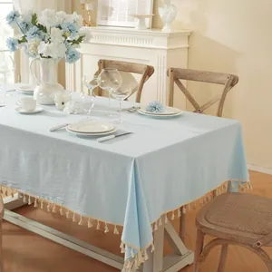 Light blue linen rectangular tablecloth with cream tassels in a cozy dining setting