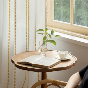 Detailed close-up of white polyester curtain with yellow diamond embroidery and fringe
