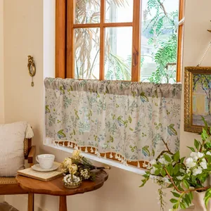 Detail of linen cafe curtain with green plant prints and decorative tassel fringe