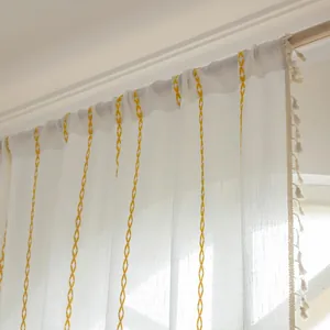 Close-up of white striped polyester curtain with yellow diamond embroidery and fringe