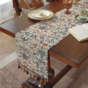 Dettaglio del runner da tavola vintage jacquard floreale con nappe su tavolo in legno