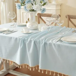 Detail of light blue tablecloth with white fringe tassels and natural fabric texture
