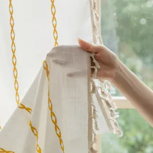Close-up of semi-sheer polyester striped curtain with yellow embroidery and side tassels